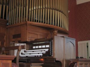 SPENCER CONGREGATIONAL CHURCH, SPENCER, MA - THREE MANUAL Spencer Congregational Church in Spencer, MA recently combined a 33 stop/36 rank Emmons-Howard pipe organ to 24/31 ranks of Allen Digital additions using a custom built 3 manual drawknob console. The resulting instrument has a specification of 57 stops/ 67 ranks. This custom designed instrument is a welcomed addition to a music program led by Sarah Rutkiewicz. The organ committee needed to address the shortcomings of their 35 year old console as well as the tonal limitations of their organ. The Emmons-Howard organ had gone through three major rebuilds in its life. It was conceived as a warm romantic organ with an orchestral breadth to its sound. However, work done in 1967 significantly altered the original design and introduced neo-baroque stops into its specification. Unfortunately, this attempt of unifying romantic and new-baroque elements was not successful. The committee decided to correct this battle of styles and replace the console. They unanimously found that the Allen Organ Company could address all their concerns with a collection of complementary digital pipe stops and a three manual Drawknob console. The new instrument’s specification includes of a new state trumpet, the addition of independent pedal stops and many new foundation stops and solo stops. The console also includes a comprehensive MIDI system with velocity sensitive keyboards.